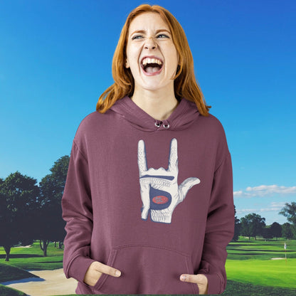 woman laughing on a golf course wearing the golf loves you hoodie in maroon. 