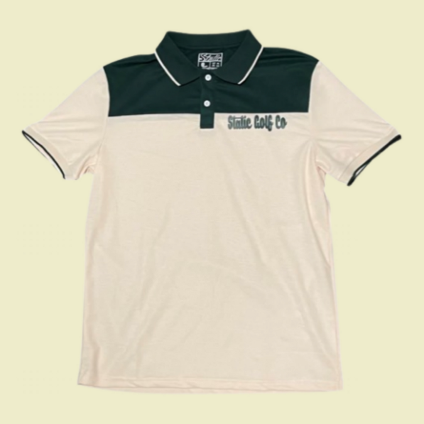 front of lil green golf polo.  forest green patch at the top, green static golf logo, on a cream polo.  unisex polo. 
